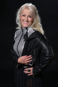 Blonde Frau mit schwarzer Lederjacke und silber-glitzerndem Oberteil