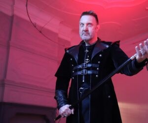 Ein Mann in einem schwarzen Mittelalter-Gewand mit einem Gehstock in der der Hand.